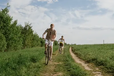 Two riders on a dirt road between fields